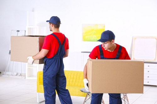 Piano moving team handling an upright piano in a Chiswick home