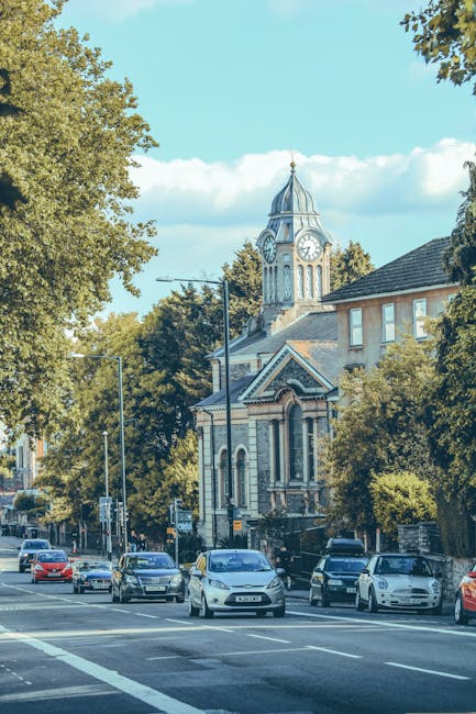 A row of terraced houses in Chiswick, London, with brick facades and white bay windows, each separated by small front gardens enclosed by low brick walls and black wrought iron fences. In front of the